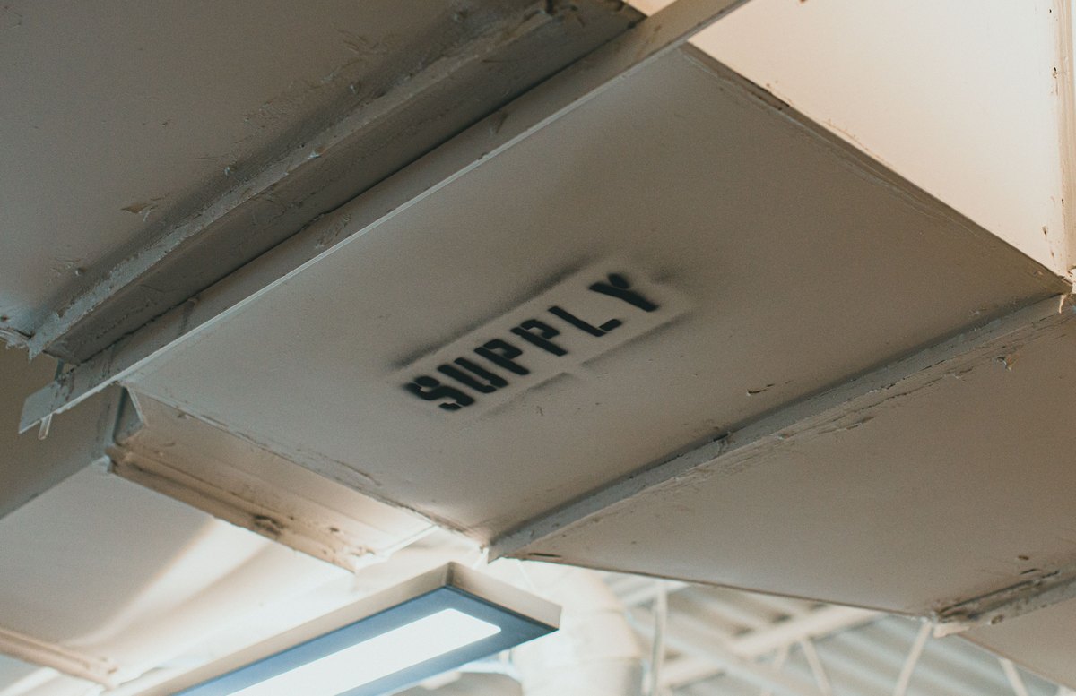 Licensed stock photograph: a sheet metal supply duct running under a ceiling.